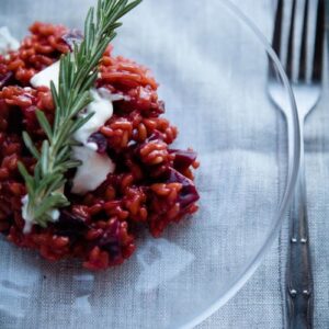Weltbestes Rote-Bete-Risotto cremig serviert in weißem Teller mit Ziegenfrischkäse und Rosmarin-Dekoration