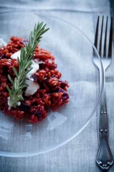 Weltbestes Rote-Bete-Risotto cremig serviert in weißem Teller mit Ziegenfrischkäse und Rosmarin-Dekoration