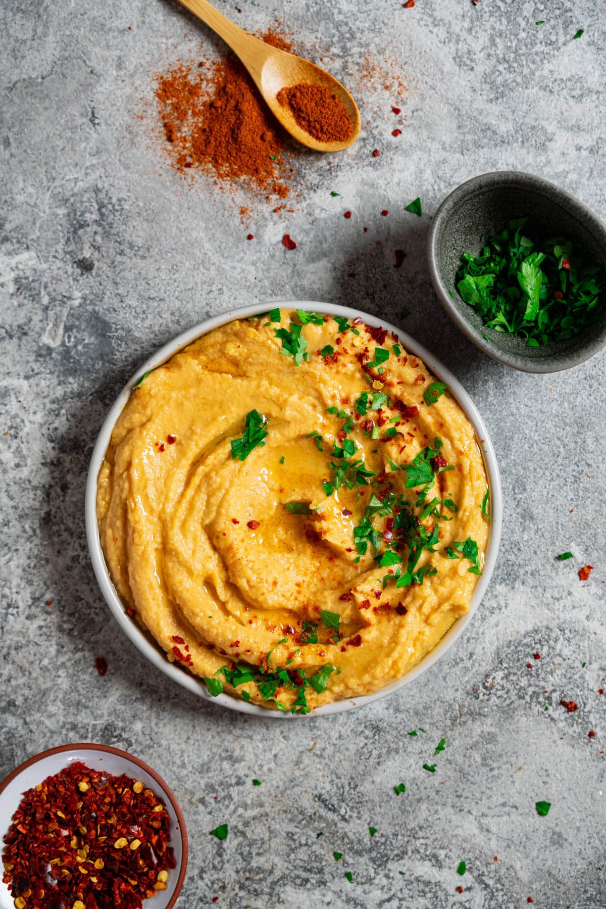 Cremiger Süßkartoffel Hummus mit Olivenöl, Petersilie und Chiliflocken garniert