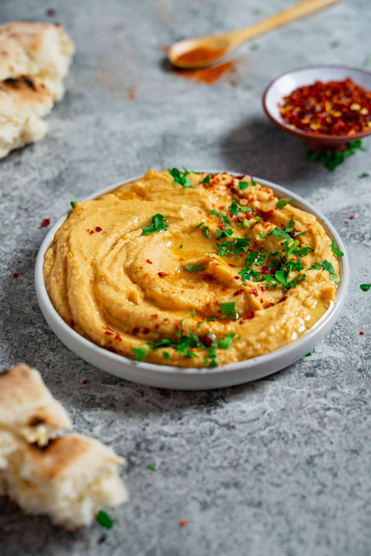 Cremiger Süßkartoffel Hummus mit Olivenöl, Petersilie und Chiliflocken garniert, dazu passt Fladenbrot