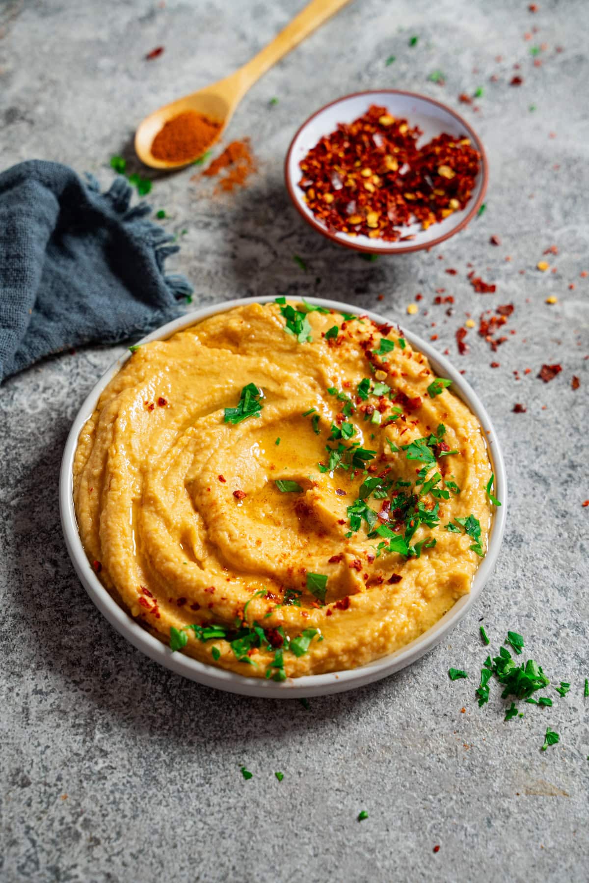 Cremiger Süßkartoffel Hummus mit Olivenöl, Petersilie und Chiliflocken garniert