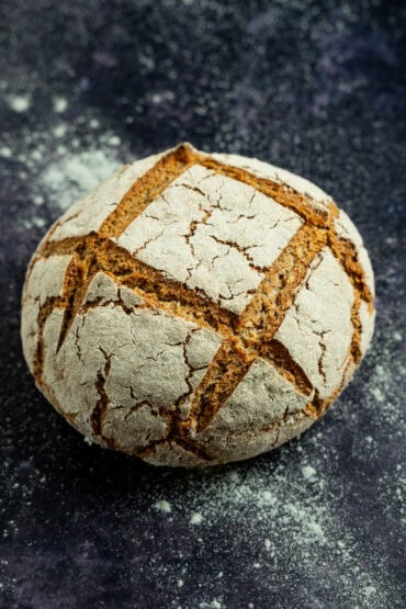 Vollkornbrot mit Sauerteig und Hefe – ganzer Brotlaib auf dunjklem Untergrund