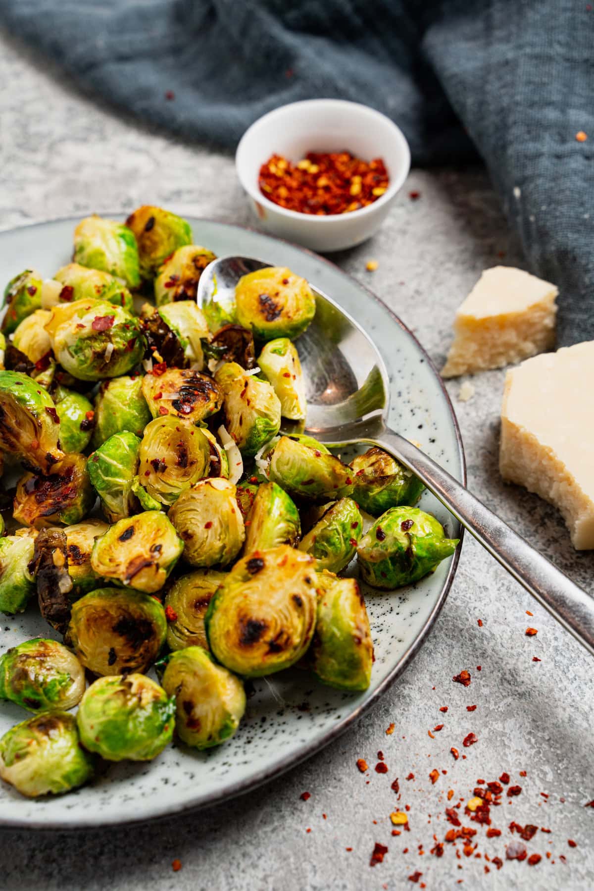 Gerösteter Rosenkohl aus dem Airfryer mit Chiliflocken und Parmesan auf grauem Teller
