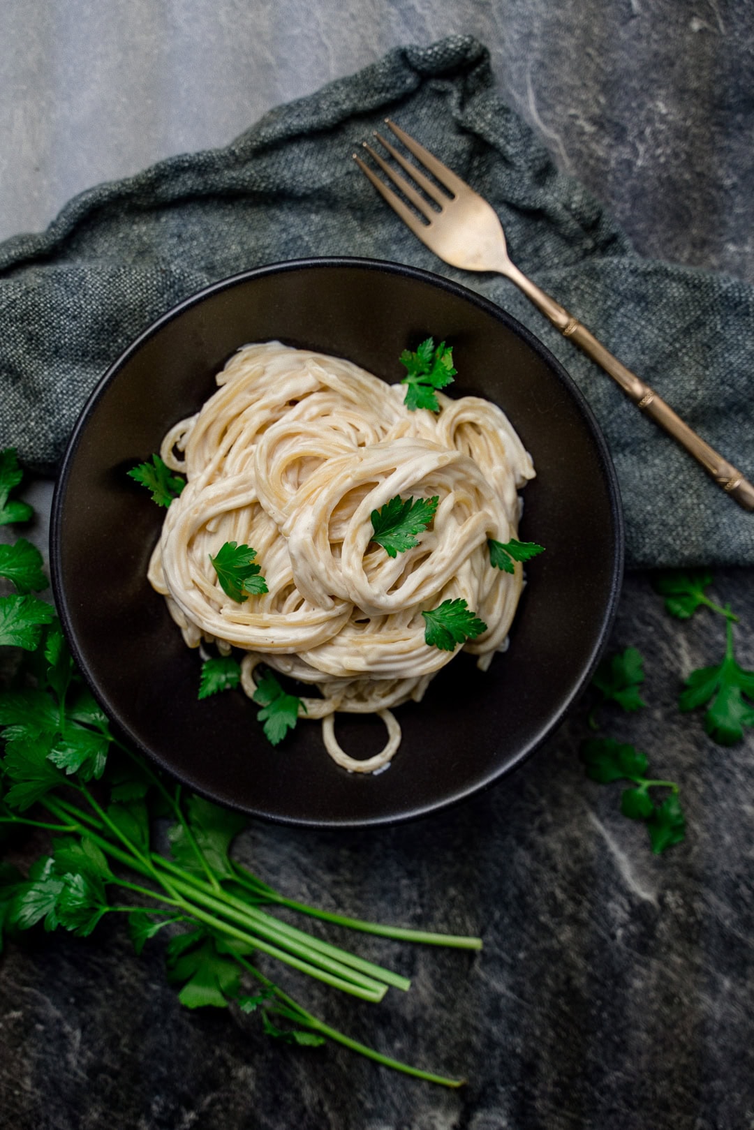 Pasta mit veganer Cashew-Käsesauce auf Teller mit Petersilie garniert